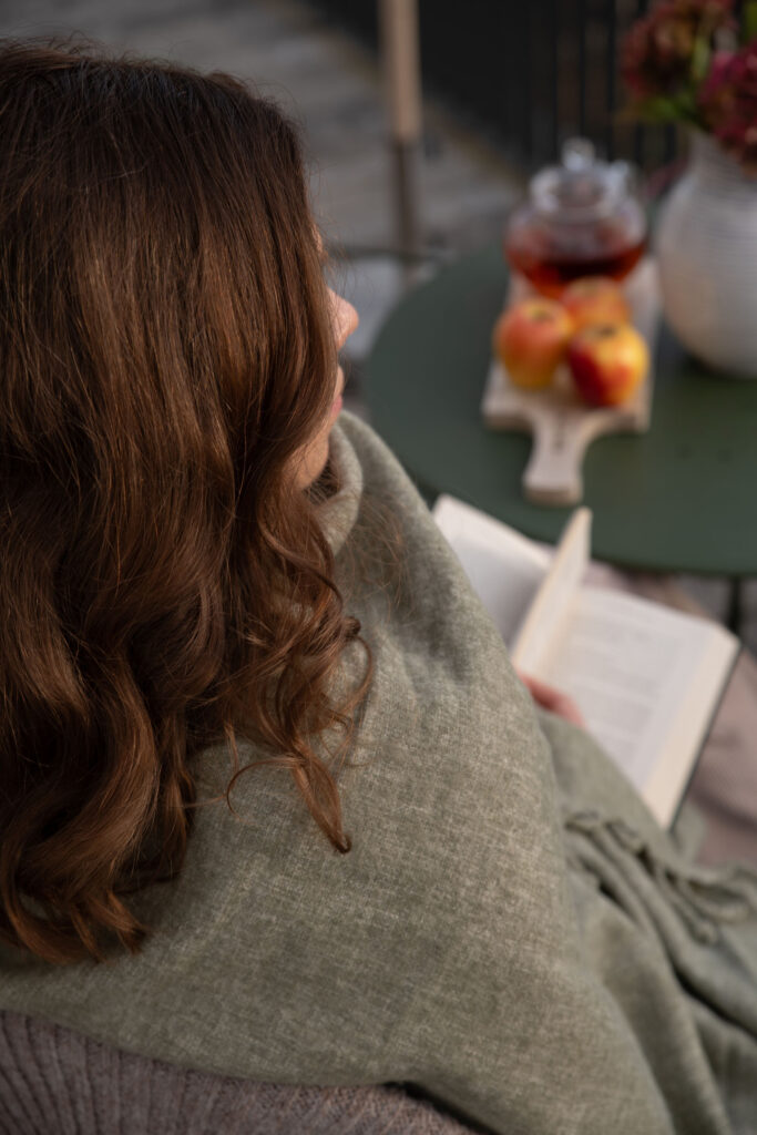 Dame liest ein Buch auf der Terrasse ihres Chalets